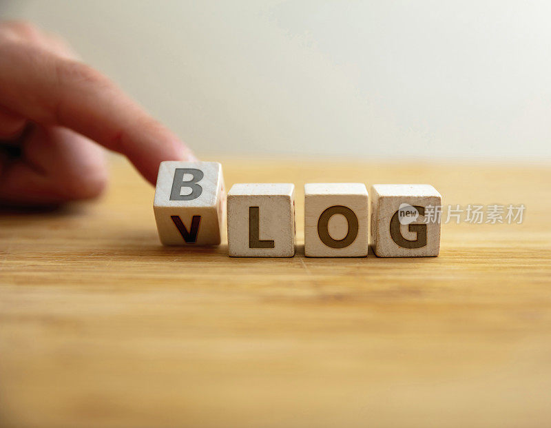 博客VS vlog的概念。手指翻转字母在木制立方体改变词博客文本vlog视频。